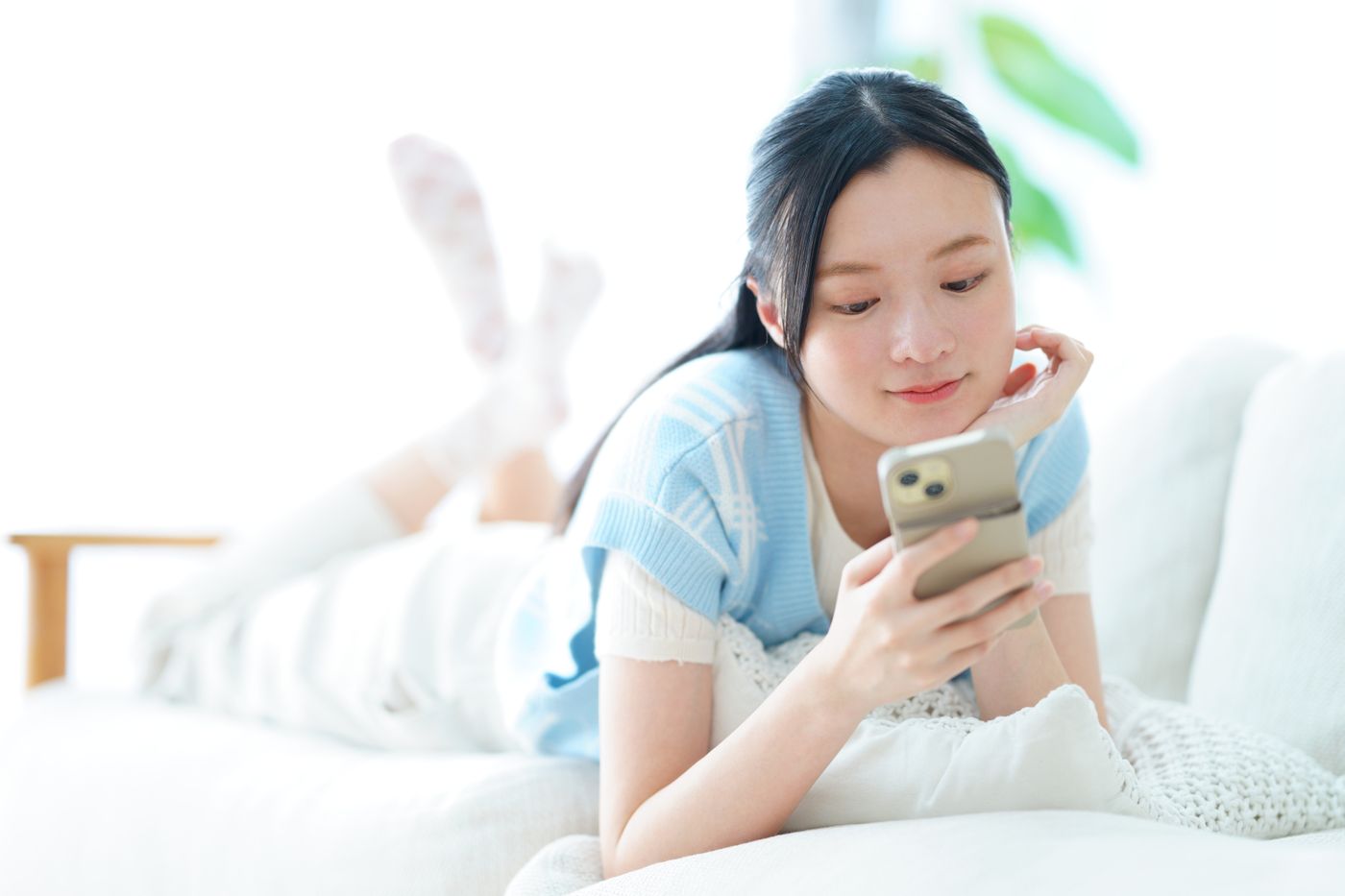 ソファでスマートフォンを見る女性